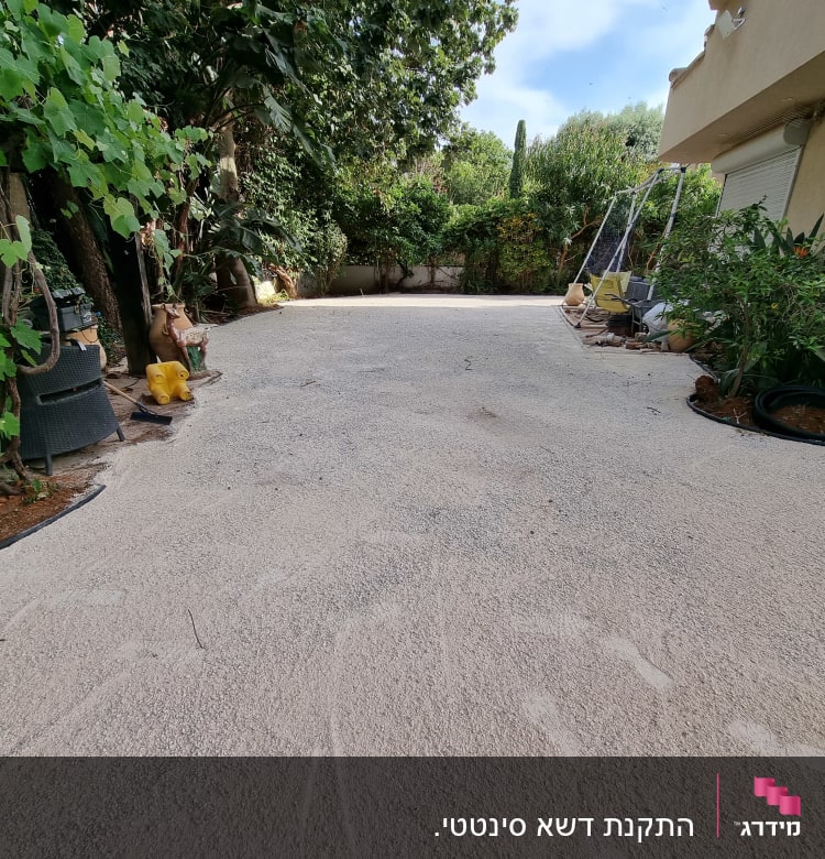 עציצים וצינורות גינה ליד שביל חצץ